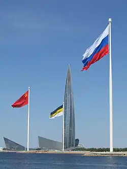The flag of the USSR on display in Saint Petersburg in 2023, alongside the black-yellow-white flag of the Russian Empire and the current-day flag of Russia.