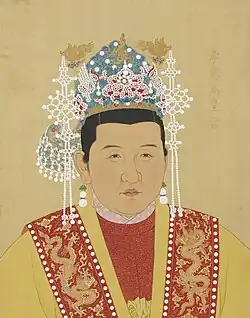 A formal, half-length portrait painting of Empress Ma. She wears a yellow imperial robe embroidered with golden dragon emblems over a red undergarment, topped by a phoenix crown (Fengguan) adorned with gold, blue, and white jewels and long pearl tassels.
