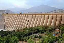 A huge concrete dam with trees at its base.
