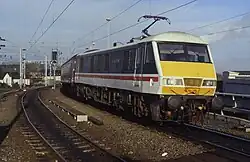 A Class 90, which is a parallelogrammical prism shape, in service. Because of the angle only the locomotive and a bit of its first coach are visible. The colour photo is taken from the track below, looking slightly up.