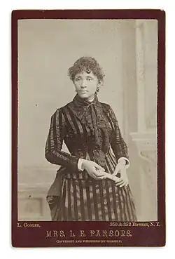 Three quarter length photograph of standing woman in striped dress