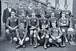Three rows of rugby players wearing their playing uniforms and caps