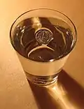 Surface tension prevents a coin from sinking: the coin is indisputably denser than water, so it must be displacing a volume greater than its own for buoyancy to balance mass.