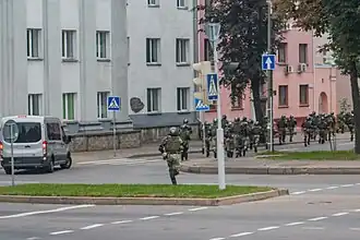 Running internal troopers in Minsk. Note the van with darkened glasses and without the registration plate: such vans are reported to be used by the government forces to bring reinforcements and detain people[311][312]