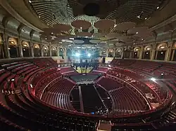 Interior of the Royal Albert Hall, showing the stage, seating tiers, and acoustic diffusers beneath the dome.