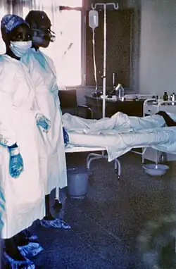 1976 photograph of two nurses in a ward, standing beside Ebola case #3 in a human patient, who died a few days later