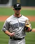 A man in grey a baseball uniform with "Toronto" and "2" on the jersey, and a black cap with the Toronto Blue Jays logo on it.