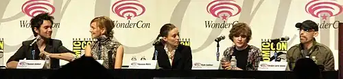 Five actors from the cast, sitting at a long table, each with a microphone. The backdrop has the WonderCon logo. The actors from left to right are Dekker, Cassidy, Mara, Gallner, and Haley.