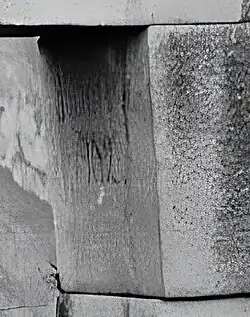 Carved inscription "A. Lizárraga 1902" on a stone of the Temple of the Three Windows.