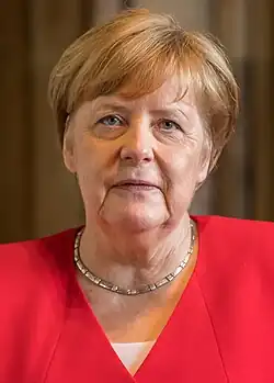 Head shot of Merkel, 64, wearing a necklace and a red blazer, and facing upwards from the camera.