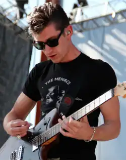 A male playing a guitar on a stage.