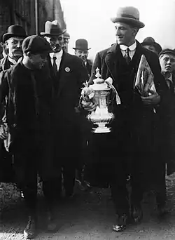 An elderly man holding the FA Cup