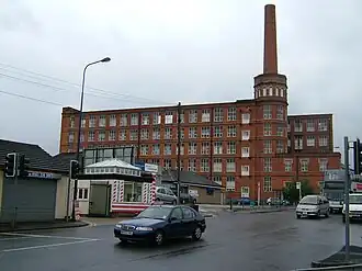 The same mill as on the right hand side of the previous photo, but this time viewed from the opposite side so the chimney is on the right. The building is clearly in better condition as it has windows but also shows many signs of decay, with some windows boarded up.