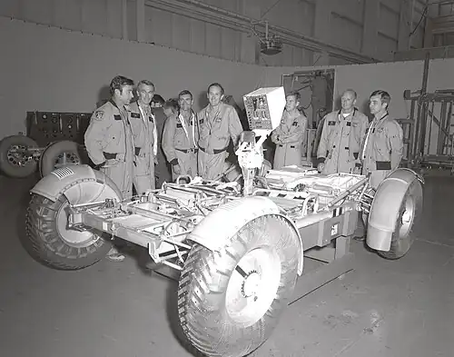 (From left to right) Astronauts John Young, Eugene Cernan, Fred Haise, Charles Duke, Anthony England, Charles Fullerton, and Donald Peterson await deployment tests of the Lunar Roving Vehicle (LRV) qualification test unit in building 4649 at the Marshall Space Flight Center (MSFC). November 1971.