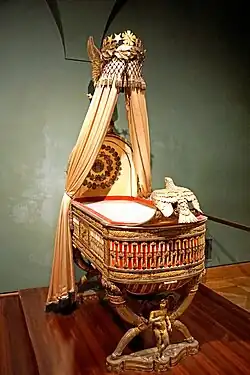 King of Rome's Cradle; by Pierre-Paul Prud'hon, Henri Victor Roguier, Jean-Baptiste-Claude Odiot and Pierre-Philippe Thomire; 1811; wood, silver gilt, mother-of-pearl, sheets of copper covered with velvet, silk and tulle, decorated with silver and gold thread; height: 216&nbsp;cm; Kunsthistorisches Museum, Vienna, Austria[80]