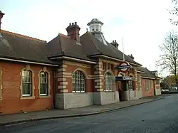 A red-bricked building with a sloping, black roof, four chimneys, and a sign that reads "UNDERGROUND" under a blue sky with white clouds