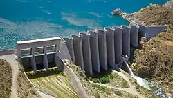 A concrete dam consisting of about ten arch shapes, with a reservoir behind it.