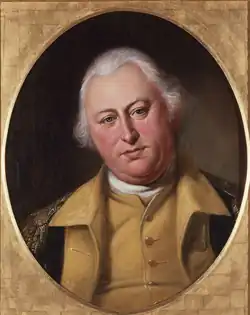 A portly, white-haired man wearing a black jacket with gold epaulets, a gold vest, and a high collared, white shirt