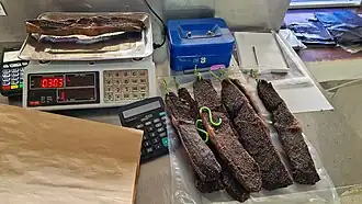 Strips of dried meat on a digital scale and counter inside a butcher shop, ready for packaging