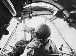 Pilot in a small cockpit wearing a parachute and leather helmet: This is a still from movie footage shot by Damien Parer.