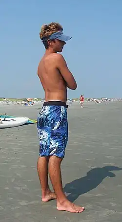 A man at the beach wearing boardshorts