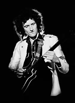 Greyscale image of a middle aged man, playing guitar.