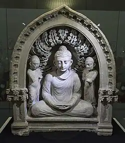 Group of Buddha seated between two monks, with two quasi-Corinthian pilasters that are here because of the influence of Greek culture during the Hellenistic period, 1st–3rd centuries, stone, State Museum of History of Uzbekistan, Tashkent