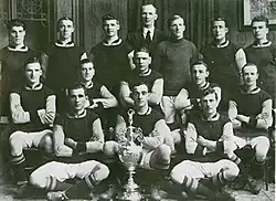 A black and white picture of Burnley posing behind a football trophy