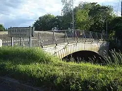 Arched bridge with metal railing. Sign showing River Parrett, Burrow Bridge.