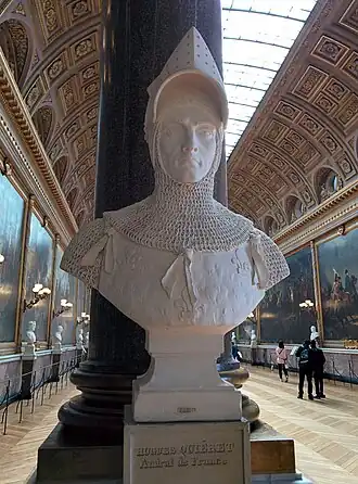 A bust in monochrome white of a man wearing late-Medieval armour