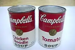 Two red and white soup cans placed side by side. One labeled "Tomato" and one labeled "Chicken Noodle"