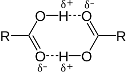 This image illustrates how two carboxylic acids, C O O H, can associate through mutual hydrogen bonds. The hydroxyl portion O H of each molecule forms a hydrogen bond to the carbonyl portion C O of the other.