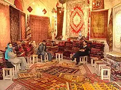 Three people sitting in a carpet shop