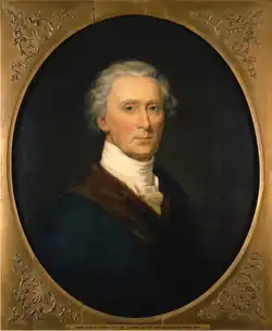 Oval portrait of a man from the bust-up, facing the viewer. He has gray hair and is wearing a blue jacket with a brown lapel, and white cravat around his neck