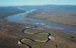 Aerial photo of the narrow horseshoe-bent Charley River flowing into the wide Yukon river with islands in the middle and nearby lakes