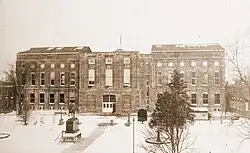 A sepia-toned photograph of a large, rectangular building.