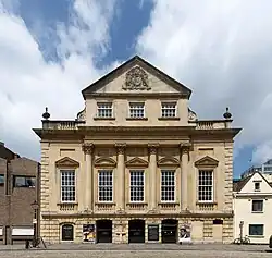 An imposing eighteenth-century building with three entrance archways, large first-floor windows and an ornate peaked gable end above.