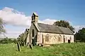 Stone building with arched windows. In the foreground are gravestones.