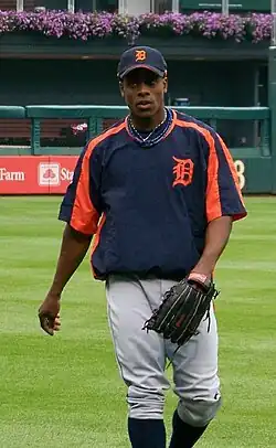 Curtis Granderson in a dark colored Detroit Tigers warm up shirt, wearing a baseball glove