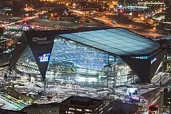 Night aerial shot of large angular modern building lit from within