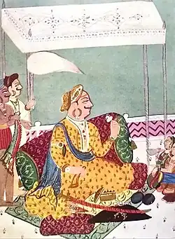 A color painting of a mustached an turbaned, seated under a canopy, surrounded by soldiers and musicians