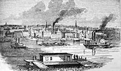 Black and white picture with boats on a river and buildings on the far side of the river