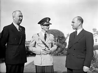 A black and white photograph of two older men alongside a young man in uniform