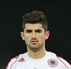 A footballer wearing a white jersey with the logo of Albanian Football Association