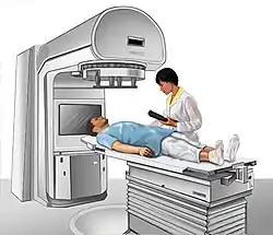 A person lies on a table under a large machine.