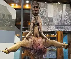 Wooden status of a woman sitting with her legs open