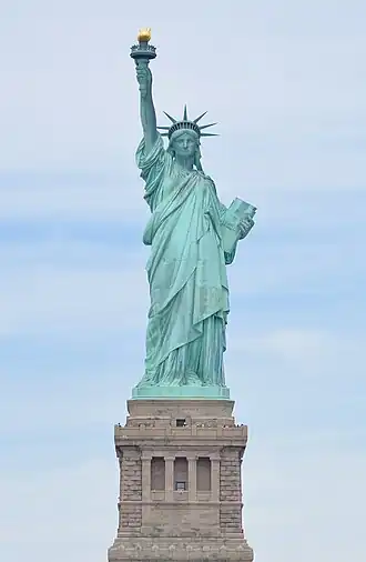 The Statue of Liberty, a large teal bronze sculpture on a stone pedestal