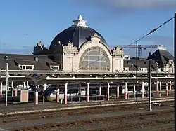 Train station with large, domed building and a high-speed train at the platform