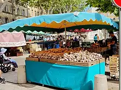 Fresh garlic bulbs arranged in crates under a market canopy in France.