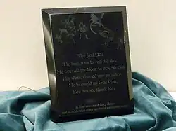 A plaque dedicated to Gary Gygax at Gen Con 2008 reading: "The first DM, He taught us to roll the dice. He opened the door to new worlds. His work shaped our industry. He brought us Gen Con, For this we thank him. In fond memory of Gary Gygax and in celebration of his spirit and accomplishments."